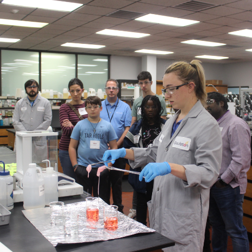 students watching chemist mix chemicals
