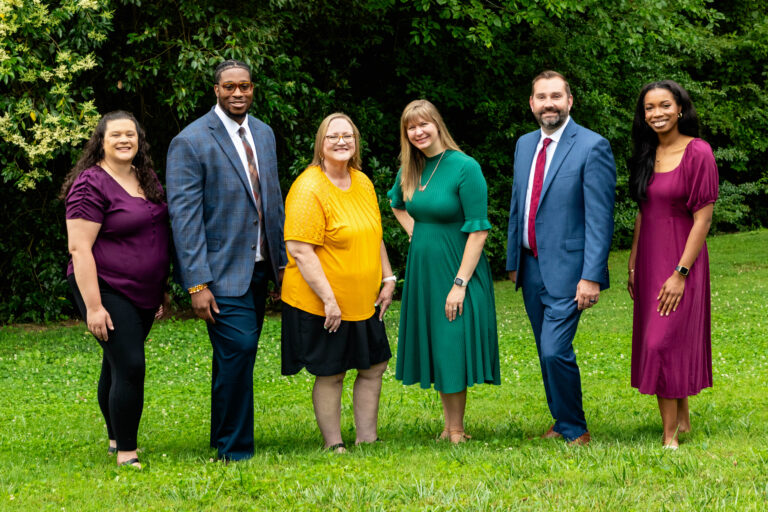 Chamber Team members dressed in bold colors, with trees in the background.